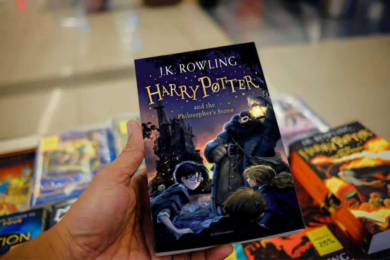 una mano tiene il libro di Harry Potter e la pietra filosofale