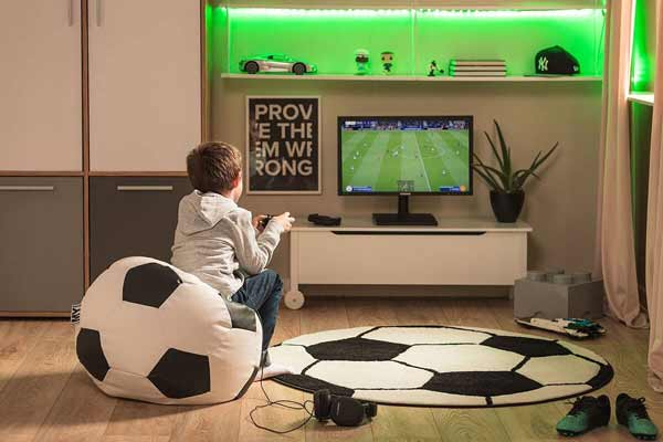 bambino gioca su un pouf in ecopelle a forma di pallone da calcio