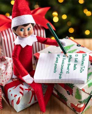 elfo sulla mensola che scrive la lista di cose da fare per Natale