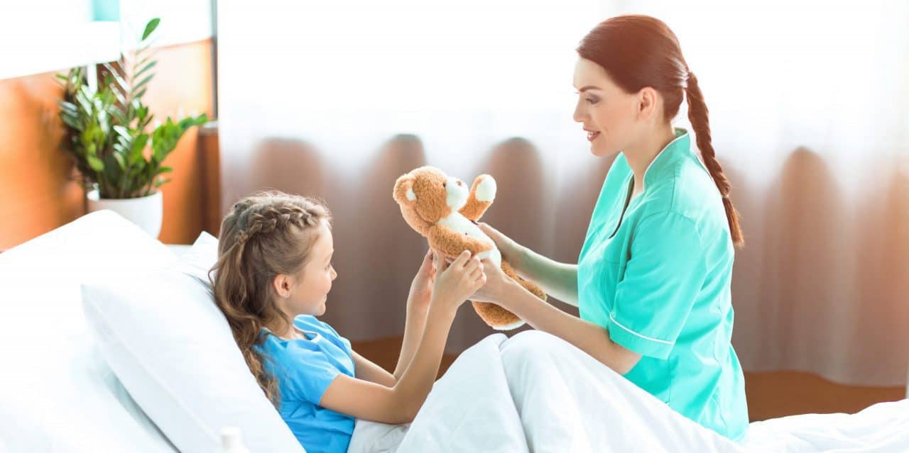 Bambina in ospedale gioca con un orsacchiotto