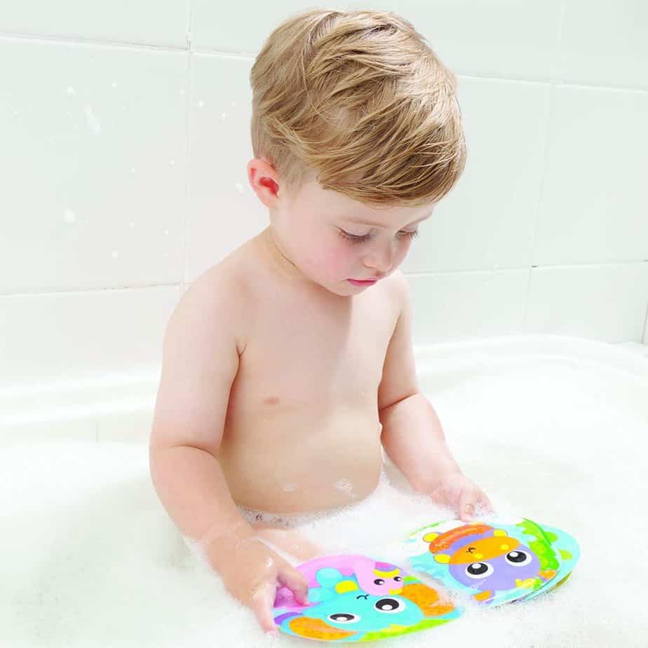 bambino di 1 anno legge un libro mentre fa il bagnetto
