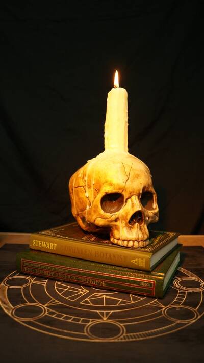 candela sopra un teschio con libri - decorazione halloween fai da te
