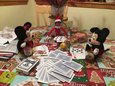 elfo birichino che gioca a carte con topolino e Minnie