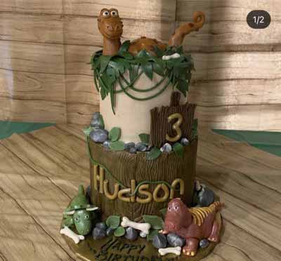 torta a tema dinosauri a due piani con tronco e vegetazione